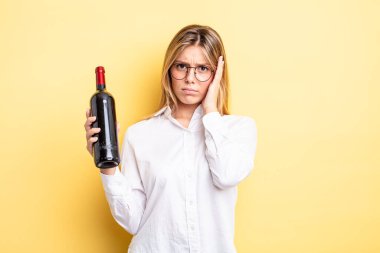 Güzel sarışın kız bıkkın, yorgun ve uykulu hissediyor. şarap şişesi konsepti