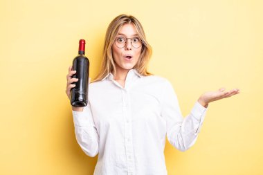 Güzel sarışın kız şaşırmış ve şok olmuş görünüyor. Çenesi düşmüş ve elinde bir nesne var. şarap şişesi konsepti