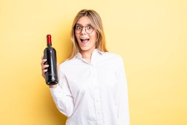 Güzel sarışın kız mutlu ve hoş bir şekilde şaşırmış görünüyor. şarap şişesi konsepti