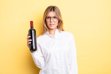 Güzel sarışın kız şaşkın ve şaşkın hissediyor. şarap şişesi konsepti