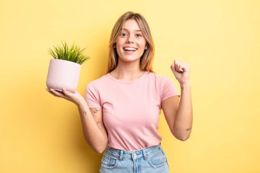 Güzel sarışın kız şokta, gülüyor ve başarıyı kutluyor. ev bitkisi kavramı