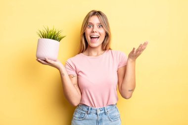 Güzel sarışın kız kendini mutlu hissediyor ve inanılmaz bir şeye hayret ediyor. ev bitkisi kavramı