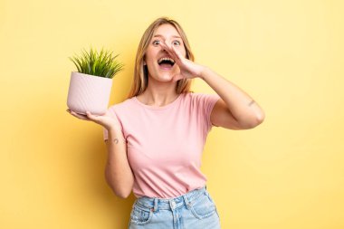 Güzel sarışın kız kendini mutlu hissediyor, elleri ağzının kenarında bağırıyor. ev bitkisi kavramı