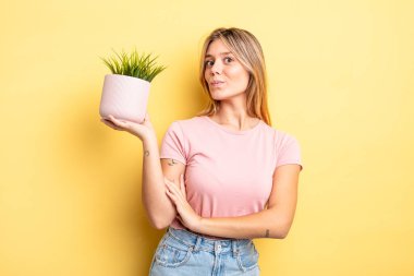 Güzel sarışın kız omuz silkiyor, kafası karışık ve kararsız. ev bitkisi kavramı