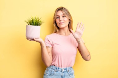 Güzel sarışın kız gülümsüyor ve arkadaş canlısı görünüyor, beş numarayı gösteriyor. ev bitkisi kavramı