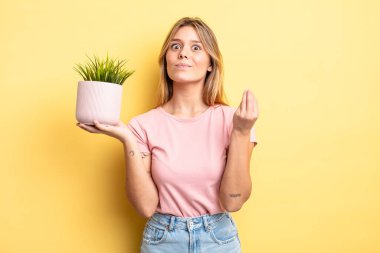 Güzel sarışın kız kapiş ya da para hareketi yapıyor, sana ödemeni söylüyor. ev bitkisi kavramı