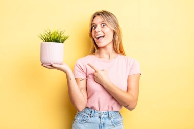 Güzel sarışın kız heyecanlı ve şaşırmış görünüyor. ev bitkisi kavramı