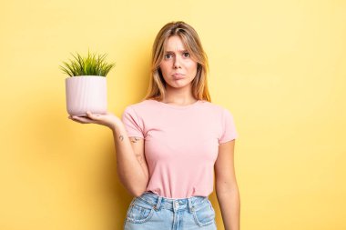 Güzel sarışın kız üzgün ve mızmızlanıyor. Mutsuz bir bakışı var ve ağlıyor. ev bitkisi kavramı