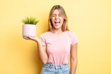 Güzel sarışın kız agresif bir şekilde bağırıyor, çok kızgın görünüyor. ev bitkisi kavramı