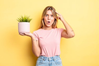Güzel sarışın kız şaşırmış görünüyor, yeni bir düşünce, fikir ya da konsept fark ediyor. ev bitkisi kavramı