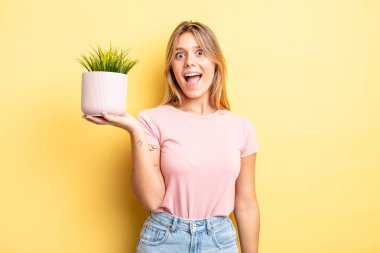 Güzel sarışın kız mutlu ve hoş bir şekilde şaşırmış görünüyor. ev bitkisi kavramı
