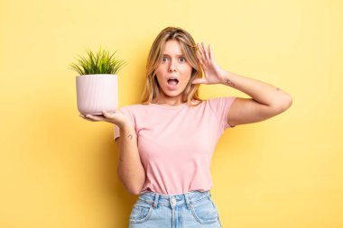 Güzel sarışın kız ellerini havaya kaldırarak çığlık atıyor. ev bitkisi kavramı