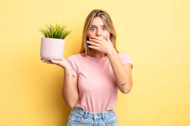 Güzel sarışın kız elleri ile ağzını kapatıyor ve şok geçiriyor. ev bitkisi kavramı