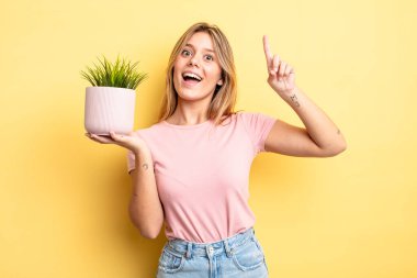 Güzel sarışın kız bir fikri fark ettikten sonra mutlu ve heyecanlı bir dahi gibi hissediyor. ev bitkisi kavramı