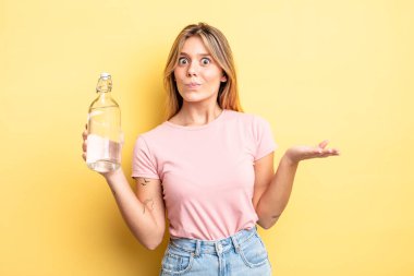 Güzel sarışın kız şaşkın, şaşkın ve şüpheci hissediyor. su şişesi kavramı