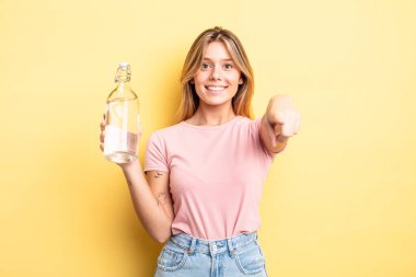 Güzel sarışın kız seni seçen kamerayı işaret ediyor. su şişesi kavramı