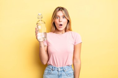 Güzel sarışın kız çok şaşırmış ya da şaşkın görünüyor. su şişesi kavramı