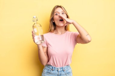 Güzel sarışın kız kendini mutlu hissediyor, elleri ağzının kenarında bağırıyor. su şişesi kavramı