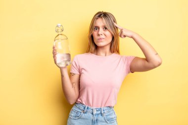 Güzel sarışın kız şaşkın ve şaşkın hissediyor, senin deli olduğunu gösteriyor. su şişesi kavramı