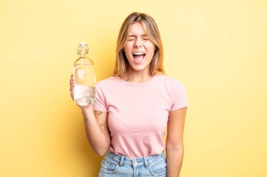 Güzel sarışın kız agresif bir şekilde bağırıyor, çok kızgın görünüyor. su şişesi kavramı