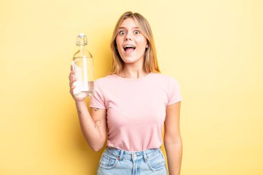 Güzel sarışın kız mutlu ve hoş bir şekilde şaşırmış görünüyor. su şişesi kavramı