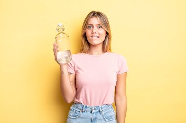 Güzel sarışın kız şaşkın ve şaşkın görünüyor. su şişesi kavramı