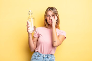 Güzel sarışın kız bıkkın, yorgun ve uykulu hissediyor. su şişesi kavramı
