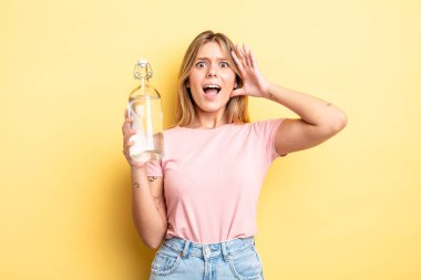 Güzel sarışın kız ellerini havaya kaldırarak çığlık atıyor. su şişesi kavramı