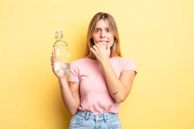 Güzel sarışın kız, ağzı ve gözleri sonuna kadar açık ve eli çenesinde. su şişesi kavramı