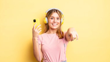 Güzel sarışın kız seni seçen kamerayı işaret ediyor. müzik konseptini dinlemek