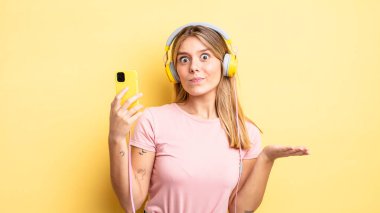 Güzel sarışın kız şaşkın, şaşkın ve şüpheci hissediyor. müzik konseptini dinlemek