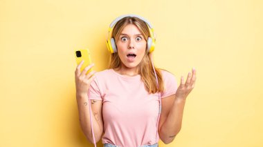 Güzel sarışın kız kendini mutlu hissediyor ve inanılmaz bir şeye hayret ediyor. müzik konseptini dinlemek