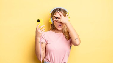 Güzel sarışın kız şok olmuş, korkmuş ya da korkmuş görünüyor. Yüzü elle kapatılmış. müzik konseptini dinlemek