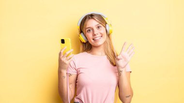 Güzel sarışın kız gülümsüyor ve arkadaş canlısı görünüyor, dört numarayı gösteriyor. müzik konseptini dinlemek