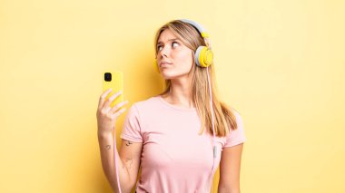 Profil görünümündeki güzel sarışın kız hayal mi kuruyor, hayal mi kuruyor yoksa hayal mi kuruyor? müzik konseptini dinlemek