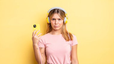 Güzel sarışın kız üzgün, üzgün ya da kızgın ve yana bakıyor. müzik konseptini dinlemek