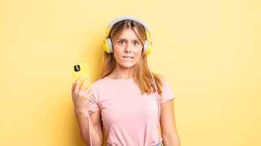 Güzel sarışın kız şaşkın ve şaşkın görünüyor. müzik konseptini dinlemek