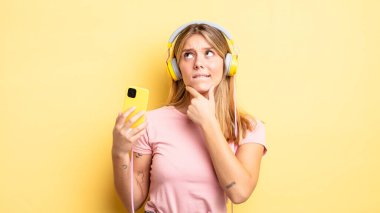 Güzel sarışın kız düşünüyor, kuşkulu ve şaşkın hissediyor. müzik konseptini dinlemek
