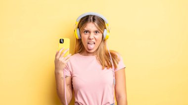 Güzel sarışın kız iğreniyor, sinirleniyor ve dilini çıkarıyor. müzik konseptini dinlemek