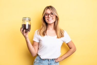 Güzel sarışın kız mutlu bir şekilde gülümsüyor, eli kalçasında ve kendinden emin. kahve çekirdeği konsepti