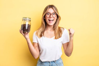 Güzel sarışın kız şokta, gülüyor ve başarıyı kutluyor. kahve çekirdeği konsepti