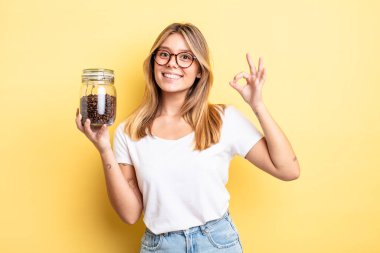 Güzel sarışın kız kendini mutlu hissediyor, iyi bir jestle onaylıyor. kahve çekirdeği konsepti