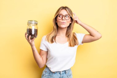 Güzel sarışın kız şaşkın ve kafası karışık, kaşınan bir kafa hissediyor. kahve çekirdeği konsepti