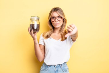 Güzel sarışın kız kendini kötü hissediyor, baş parmağını kaldırıyor. kahve çekirdeği konsepti