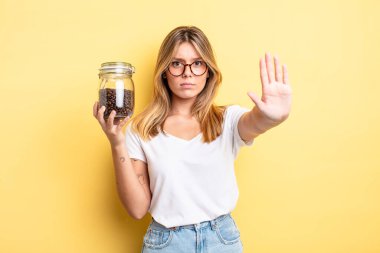 Güzel sarışın kız ciddi görünüyor. Avuç içini gösteriyor. Durma hareketi yapıyor. kahve çekirdeği konsepti