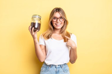 Güzel sarışın kız mutlu hissediyor ve heyecanla kendini işaret ediyor. kahve çekirdeği konsepti