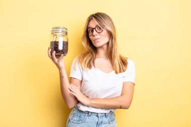 Güzel sarışın kız omuz silkiyor, kafası karışık ve kararsız. kahve çekirdeği konsepti