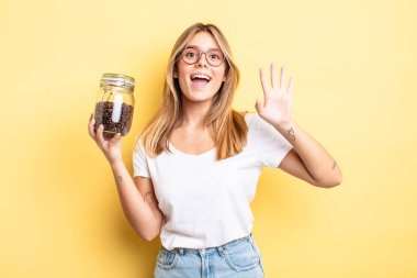 Güzel sarışın kız mutlu bir şekilde gülümsüyor, el sallıyor, hoş geldin diyor ve seni selamlıyor. kahve çekirdeği konsepti