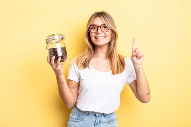 Güzel sarışın kız gülümsüyor ve arkadaş canlısı görünüyor. Bir numarayı gösteriyor. kahve çekirdeği konsepti