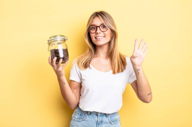 Güzel sarışın kız gülümsüyor ve arkadaş canlısı görünüyor, dört numarayı gösteriyor. kahve çekirdeği konsepti